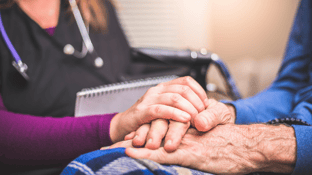 Nurse holding the hand of an elderly hospice patient