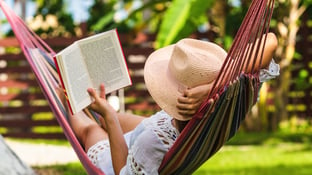 Woman relaxing in hammock while reading a book